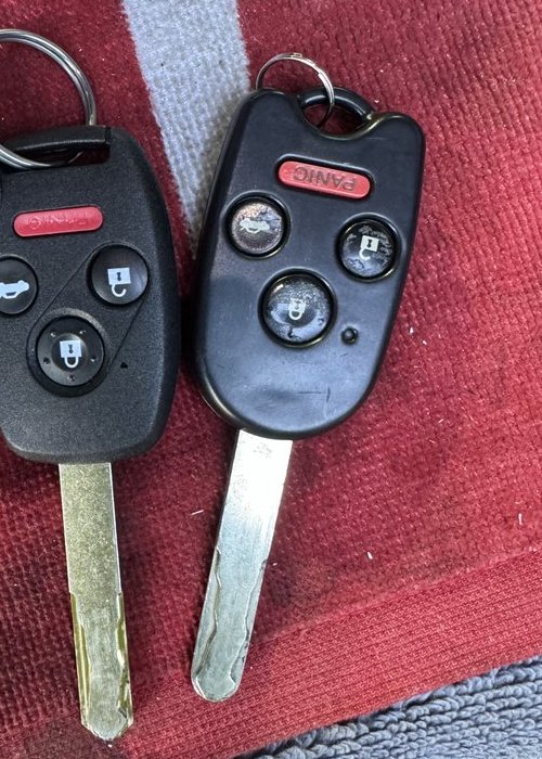 A new remote head key laid beside the customer's worn original