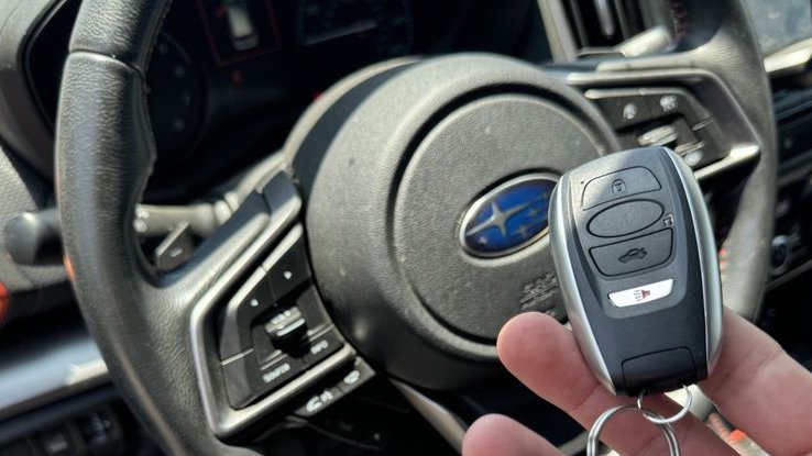 A smart fob held up in front of the steering wheel after programming